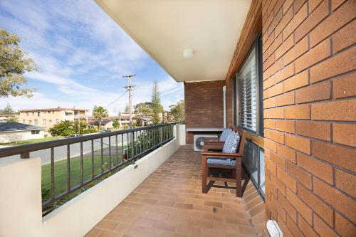 a balcony with a brick wall and a window at Bowling Greens in Tuncurry