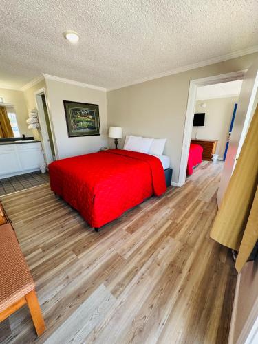 a bedroom with a red bed and wooden floors at Oak Grove Inn in Branson