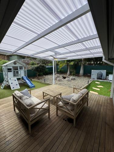 a patio with awning and two chairs and a table at Four Palms Forster Luxe Spacious Pet Friendly in Forster