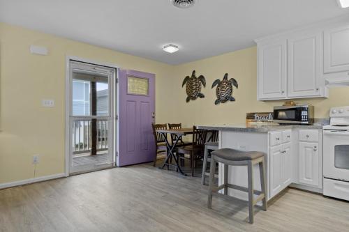 a kitchen with white cabinets and a purple door at Boardwalk Shores C Duplex in Atlantic Beach
