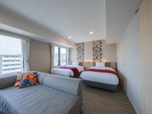 a hotel room with two beds and a couch at Hotel SUI Kyoto Kiyomizu in Kyoto