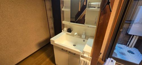 a bathroom with a white sink and a mirror at Guesthouse Kaede in Takayama