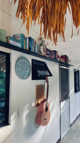 a guitar is hanging on a wall with a clock at Duck & Drift - a Sleeper Hostel - Just 1,7km from Airport in Puerto Princesa City