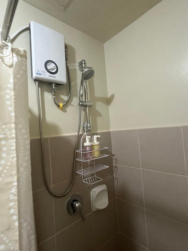 a shower head in a bathroom with a shower curtain at The Charmed Place Iloilo in Iloilo City