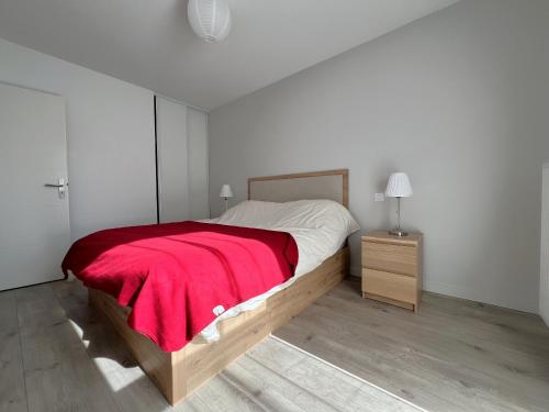 une chambre avec un grand lit avec une couverture rouge dans l'établissement Appartement à Arcachon avec terrasse, proche plage et parking - FR-1-474-268, à Arcachon