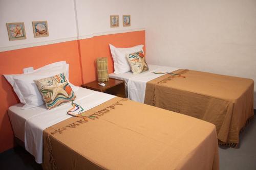 two beds in a room with orange walls at Pousada Mirante das Fitas in Arraial d'Ajuda