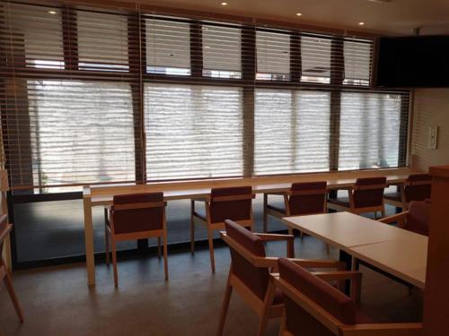 a room with tables and chairs and a large window at Smile Hotel Namba in Osaka