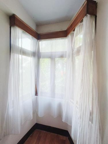 a window with white curtains in a room at Hotel Sakura Mountain view Near Darjeeling Toy Train Station in Darjeeling