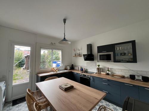 une cuisine avec des placards bleus et une table en bois dans l'établissement Arcachon : Maison 3 chambres idéale famille/amigos - FR-1-319-597, à Arcachon