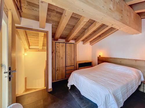 une chambre avec un lit blanc et des plafonds en bois dans l'établissement Appartement neuf 2 chambres près des pistes à Combloux avec parking - FR-1-560-158, à Combloux