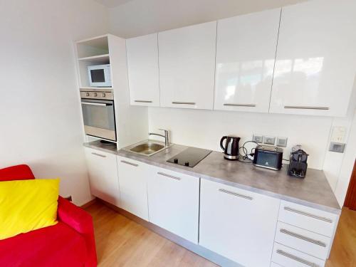 - une cuisine blanche avec des placards blancs et un canapé rouge dans l'établissement Studio climatisé avec terrasse et wifi proche plages à Menton - FR-1-196-377, à Menton