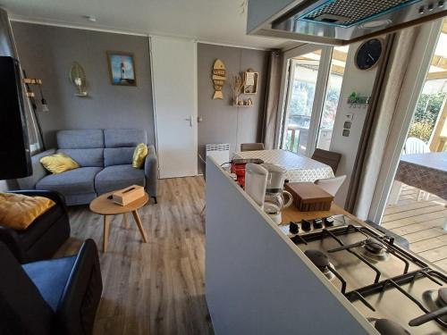 Il comprend une cuisine et un salon avec un canapé et une cuisinière. dans l'établissement Mobil-home confortable proche de l'Atlantique - FR-1-426-577, à Saint-Hilaire-de-Talmont