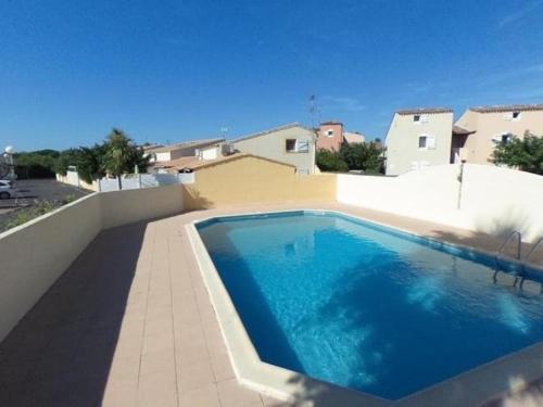 - une piscine sur le côté d'une maison dans l'établissement Pavillon Cap d'Agde T2 Mezzanine 4 Pers avec Terrasse - FR-1-749-96, au Cap d'Agde