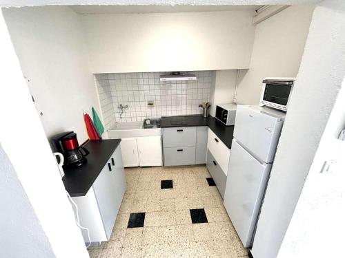 - une petite cuisine avec des appareils blancs et des comptoirs noirs dans l'établissement Appartement 2 Pièces, Terrasse Vue Mer, Parking Privé - FR-1-229C-108, à Port-la-Nouvelle
