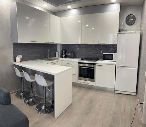 a kitchen with white cabinets and a counter with stools at Сучасна та простора квартира в гарному районі міста біля парку in Irpin'
