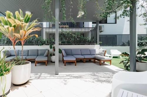 a patio with couches and plants in a building at Coolum Gem with BBQ & Stunning Pool in Coolum Beach
