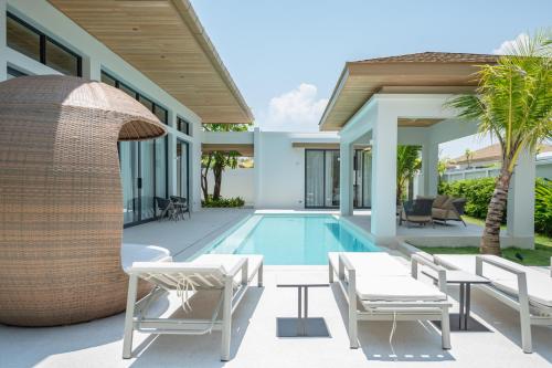 a villa with a swimming pool and a resort at Mouana Breeze Mai Khao VIP 4-bedroom Pool Villa 9913 in Mai Khao Beach
