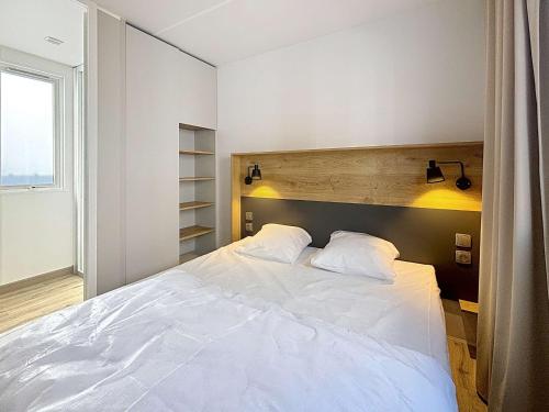 a bedroom with a large white bed with two pillows at Mobil-home Confort 4 pers, plage à 200m, piscine chauffée, terrasse Sud, parking, wifi inclus - FR-1-361A-81 in Jullouville-les-Pins