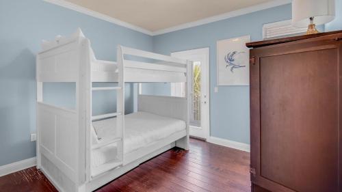 a white bunk bed in a room with wooden floors at The Bluefin - Luxury Beach Home! in Destin