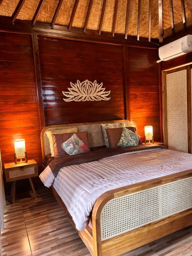 a large bed in a room with wooden walls at Balikaru Living in Penebel
