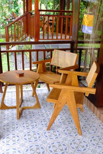 two wooden benches and a table on a porch at Balikaru Living in Penebel