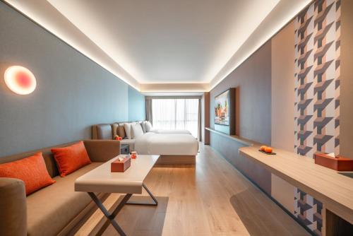 a room with a couch and a bed in a room at Orange Hotel Foshan Shunde Happy Coast Scenic Area in Shunde
