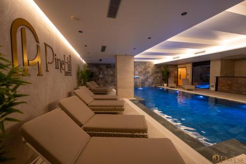 a hotel lobby with a pool and lounge chairs at PineHill Hotel, Restaurant , Pool & Spa - RAZEM in Razëm