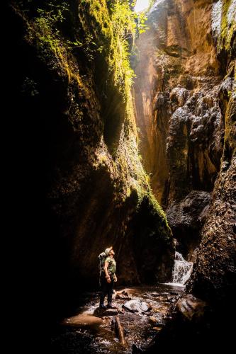 a man standing in front of a waterfall in a canyon at Hosteria Taita Pacho in Penipe