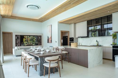 a kitchen and dining room with a table and chairs at Mouana Breeze Mai Khao VIP 4-bedroom Pool Villa 9913 in Mai Khao Beach