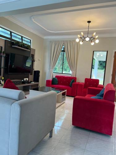 a living room with red couches and a tv at Green Cove Villa A Famosa Karaoke Netflix Private pool in Simpang Empat