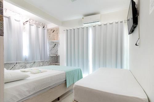 a white room with two beds and a window at POUSADA los SABABA in Morro de São Paulo