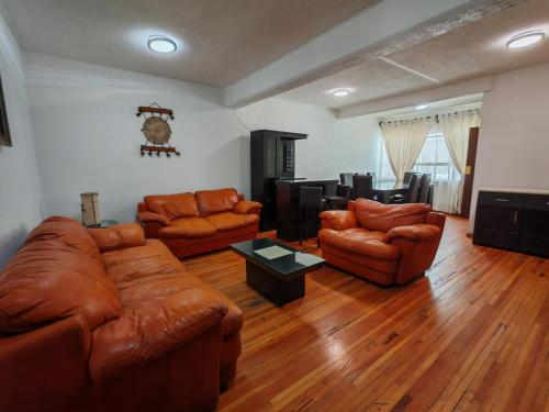 a living room with leather furniture and a table at Departamento cerca de Reforma y Chapultepec - atrás Torre Mayor in Mexico City