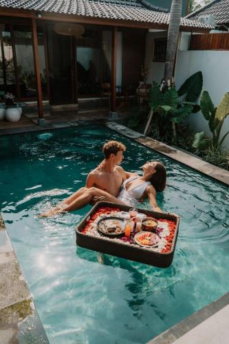 a man and a woman sitting in a swimming pool at Maddu Suites in Ubud