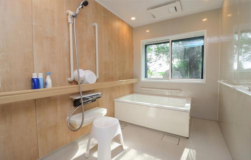 a bathroom with a tub and a toilet and a sink at 佐渡の隠れ家 ときの穂 in Sado