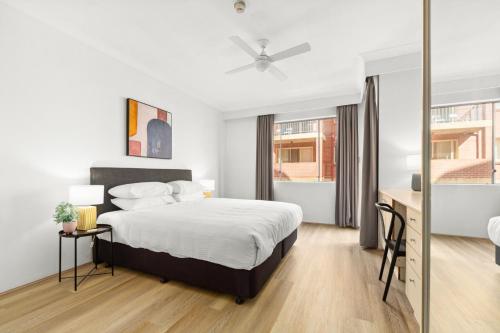 悉尼Bright Inner-West Stay with Pool Access的一间卧室，配有一张床、一张书桌和一扇窗户