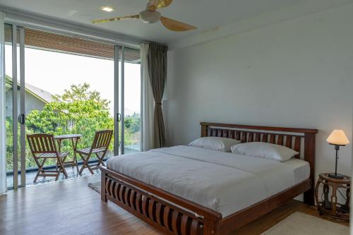 a bedroom with a bed and a balcony at Aislinn Villa - Luxury Private Pool Villa by WOW Holiday Homes in Pantai Cenang