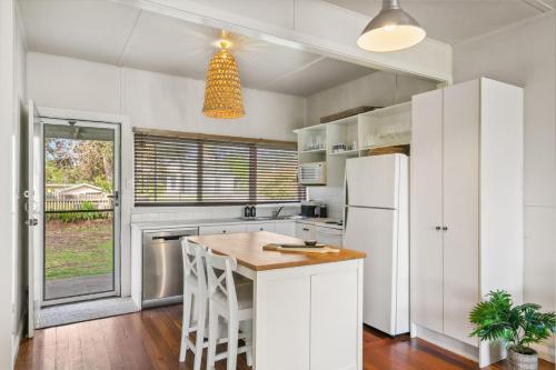 Una cocina con gabinetes blancos y un refrigerador blanco. en Werri Beach Shack, en Gerringong