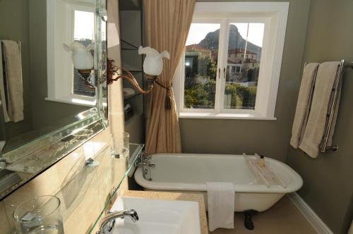 a bathroom with a tub and a sink and a window at Abbey Manor Luxury Guesthouse in Cape Town