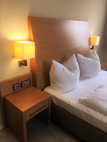 a bed with two pillows and a night stand next to a bed at Pension Am Pollingpark in Dessau