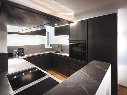 a kitchen with black cabinets and stainless steel appliances at Paradeis Apartments A19 in Mühlbach