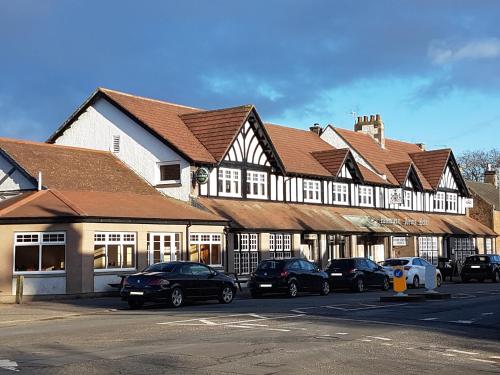 a row of buildings with cars parked in a parking lot at The Panmure Arms Hotel in Edzell