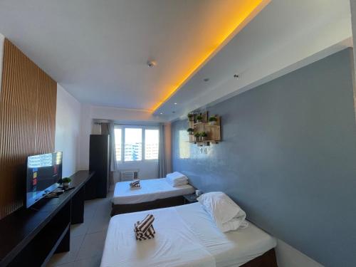 a hotel room with two beds and a television at Premiere Haven MOA Staycation in Manila