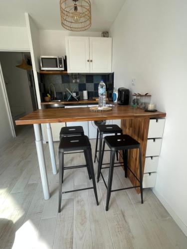 une cuisine avec une table en bois et deux tabourets dans l'établissement Appartement au pied du port, à Canet