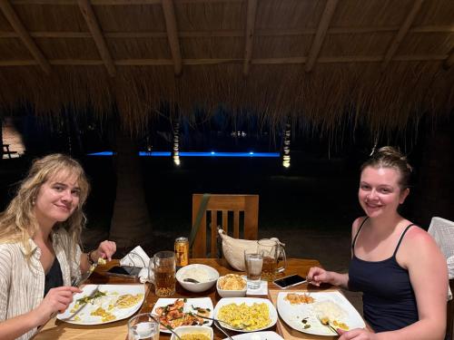 two women sitting at a table eating food at Agro Village Resort , Kalpitiya in Kalpitiya