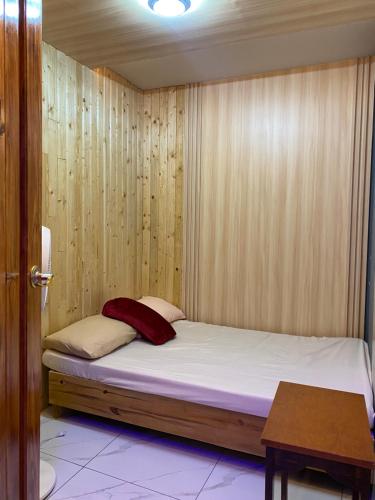 a bed in a room with a wooden wall at 3 Bedroom Condotel Ina Mansion Baguio City in Baguio