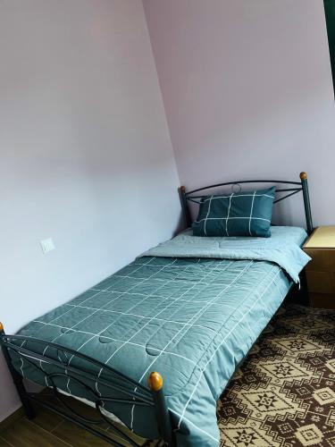 a bed in a room with a green comforter and pillows at Sunshine 2 in Leonidion