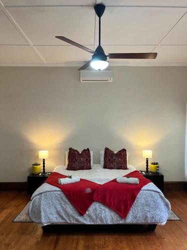 a bedroom with a bed with red blankets and a ceiling fan at Toni's Cottage in Graaff-Reinet