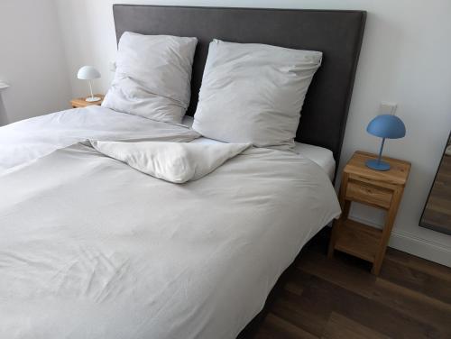 Winzervilla Kammerhof - 3x stilvolle & geräumige FeWos mit Moselblick, 2-12 Gäste buchbar, direkt am Moselradweg في برونبيبيرغ: سرير بملاءات ومخدات بيضاء بجانب طاولة