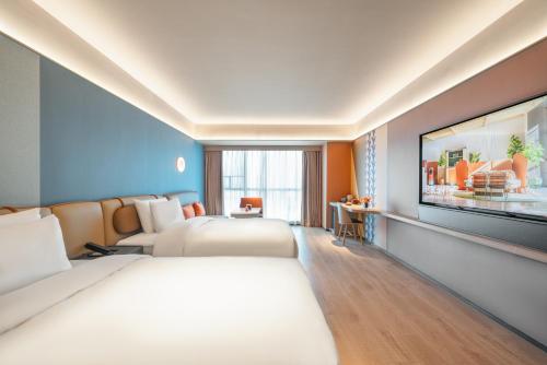 a hotel room with two beds and a tv at Orange Hotel Foshan Shunde Happy Coast Scenic Area in Shunde