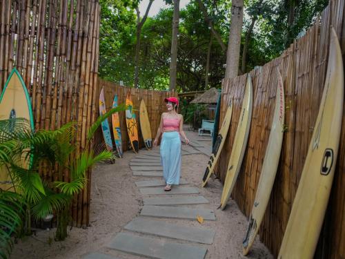 a woman walking through a fence with surfboards at Beach House Camp in Na Jomtien